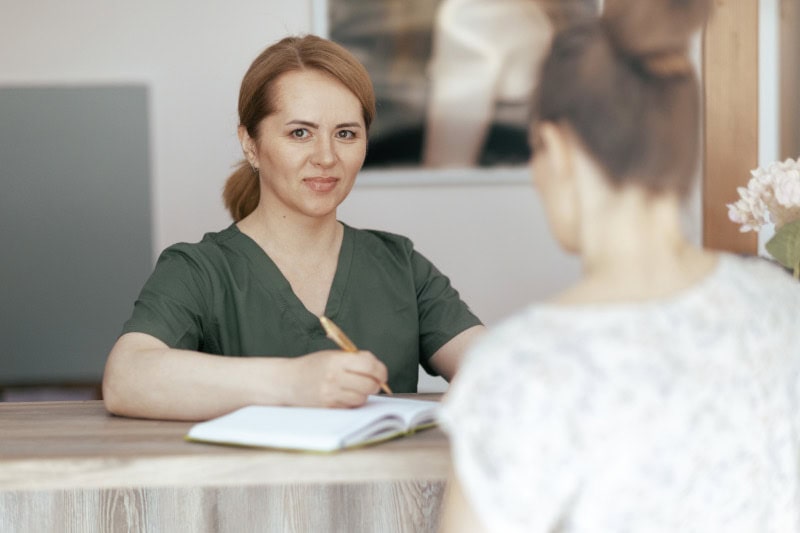 Massage therapist meeting new client for the first time discussing service options.